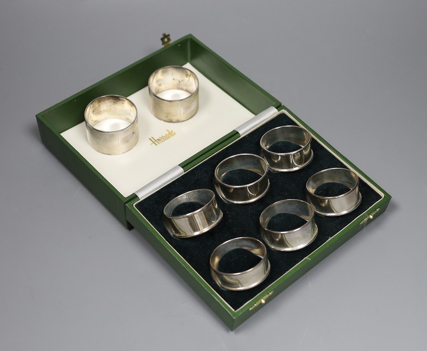 A cased set of six modern silver napkin rings and one other pair of engine turned silver napkin rings.